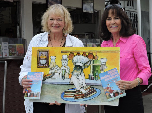 Carol presenting Gloria with a Chef Daisy print from her Daisys Reality Show Adventure book